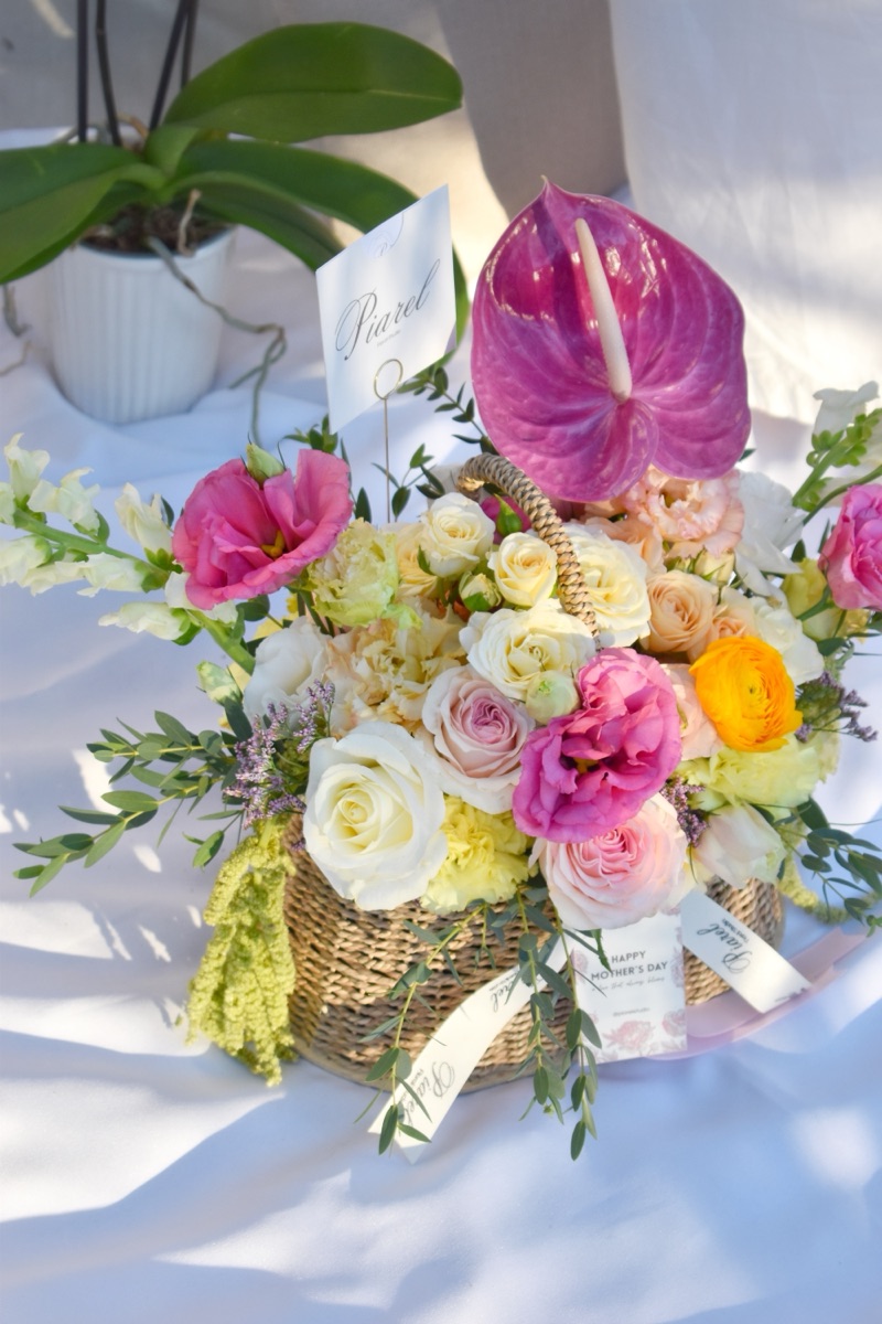 Canasta Corazón de mamá — rosas, lisianthus, perritos, mini rosas, ranunculus y anturio en canasta tejida con tonos vibrantes